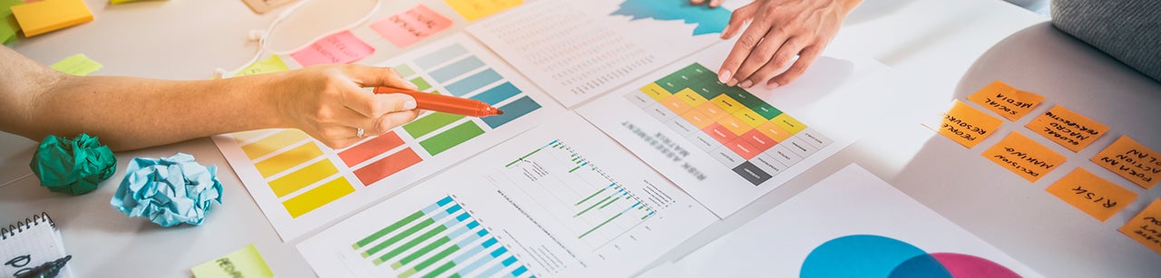 Manos trabajando con gráficos de colores y post it