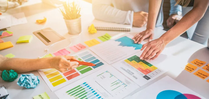 Personas trabajando en una mesa con gráficos