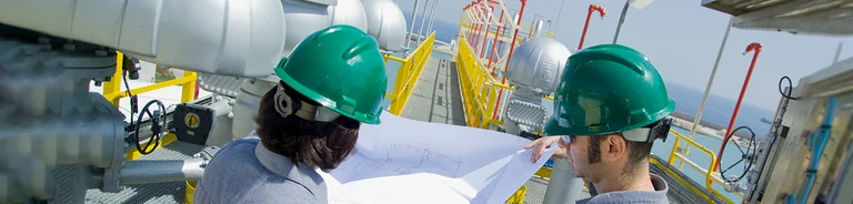 Workers wearing helmets consulting a map