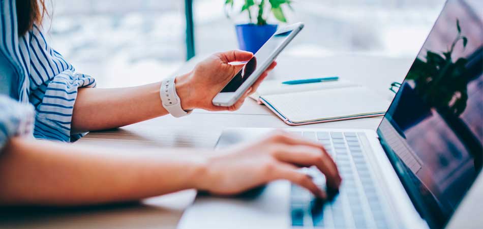 Hand holding a phone while typing