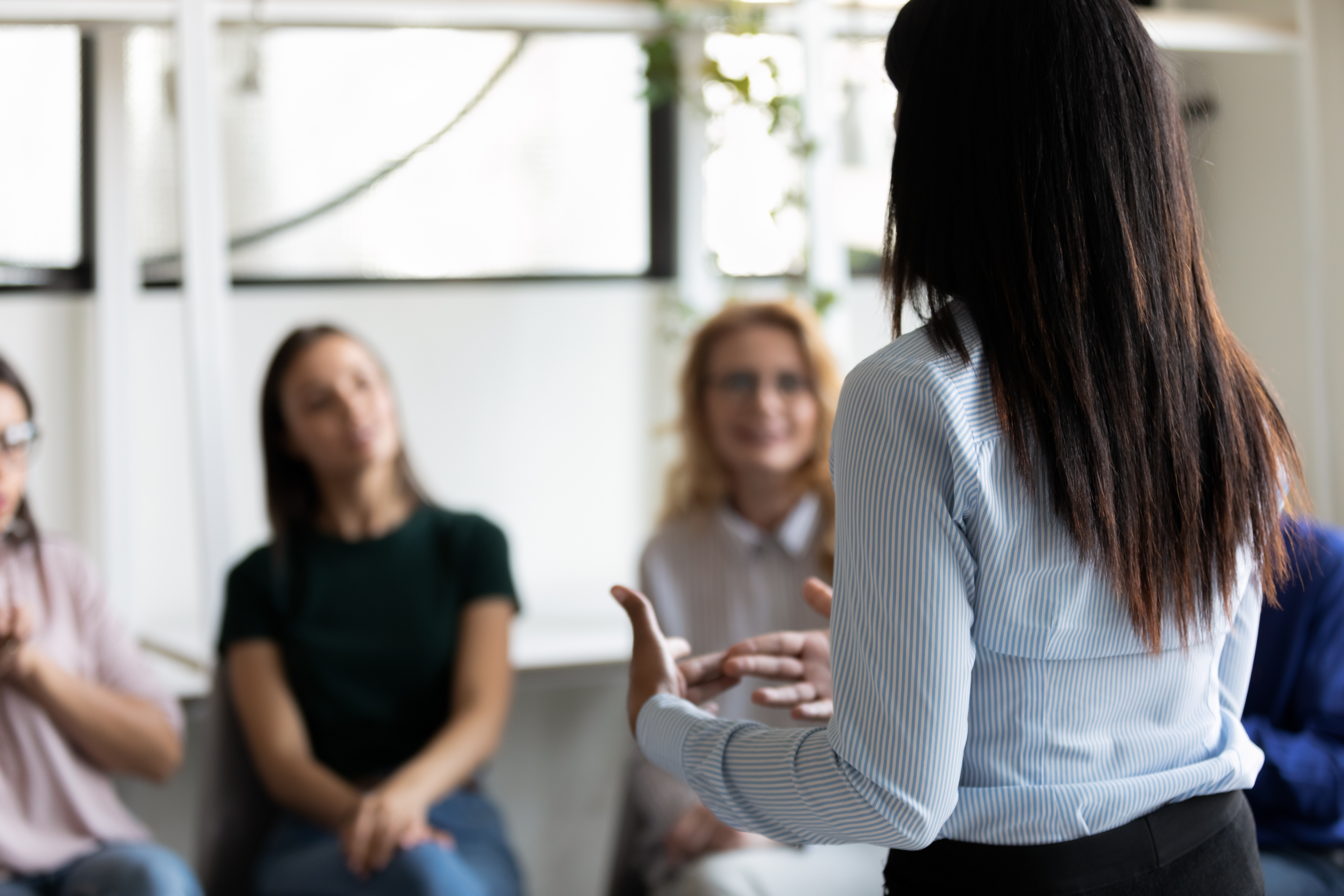 Mujer de espaldas charlando con otras mujeres