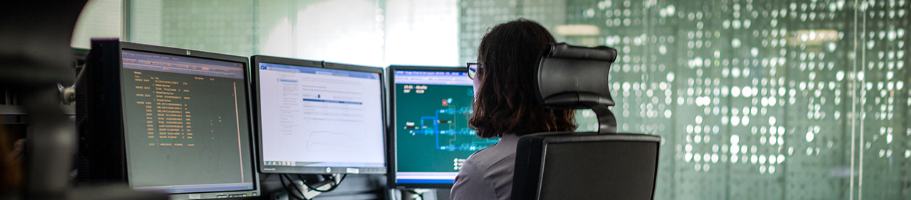 Female employee working with three screens